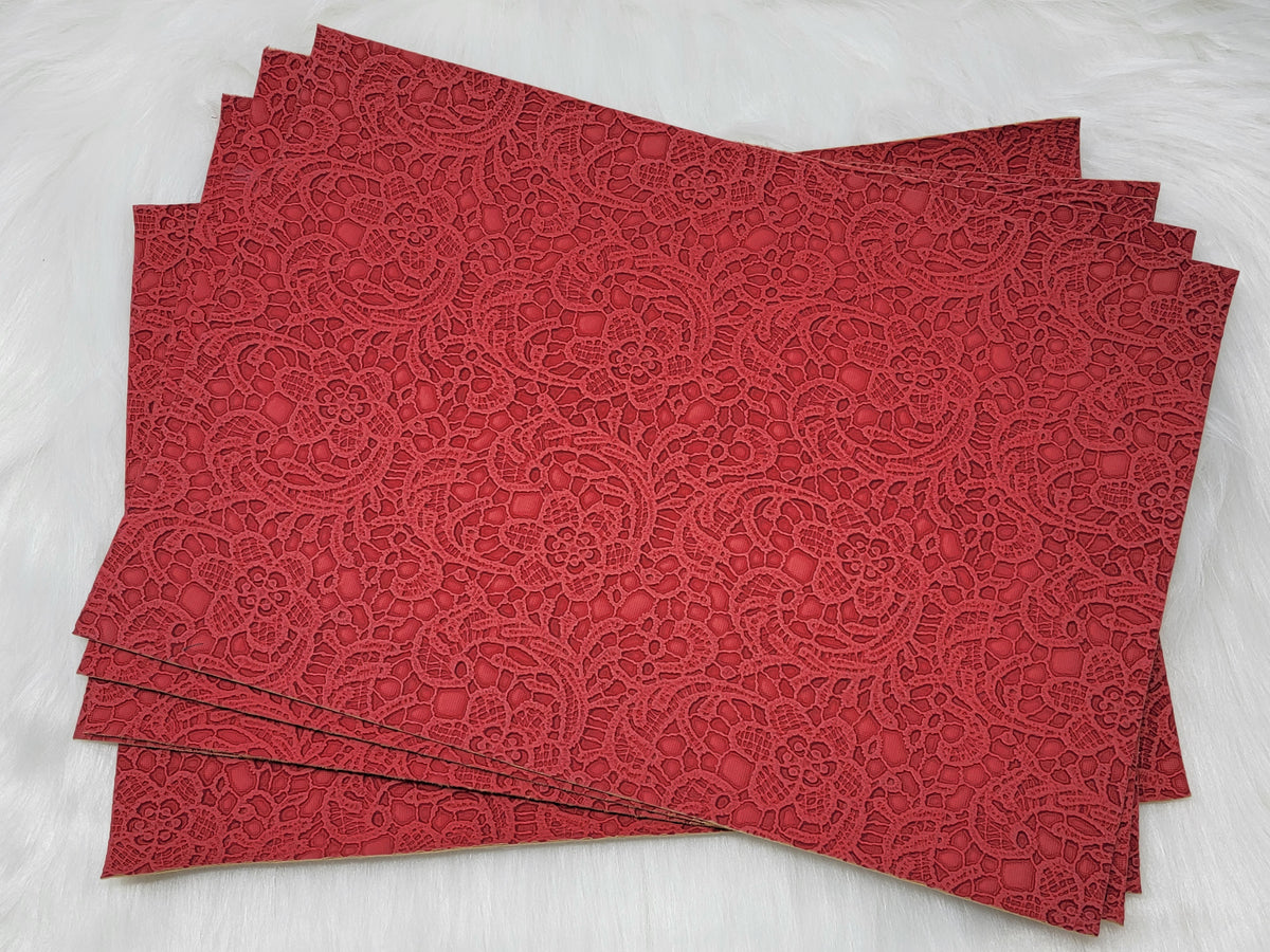 Stack of #59 red faux leather sheets embossed with a tooled floral scroll pattern