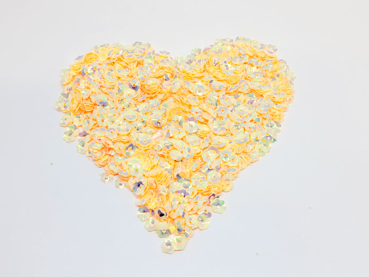 Heart-shaped pile of 6mm iridescent flower sequins in creamsicle