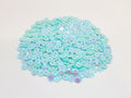 Pile of 6mm round seafoam sequins with centre holes, on a white background
