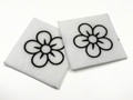 Two beading patterns printed in black on stiff white pellon squares, showing a five-petal flower