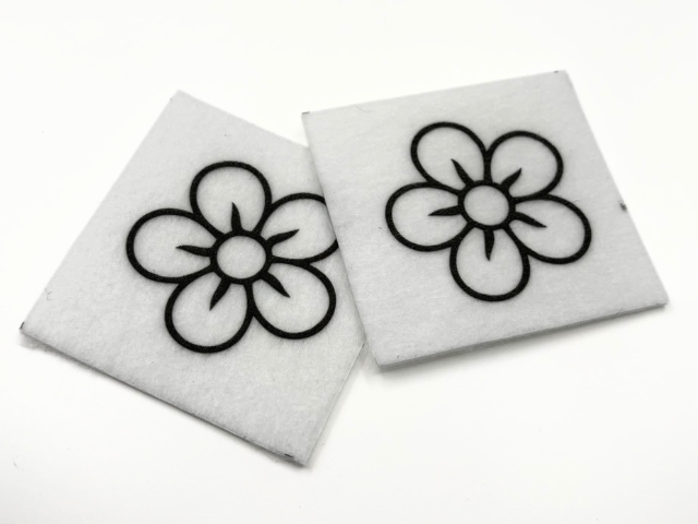 Two beading patterns printed in black on stiff white pellon squares, showing a five-petal flower
