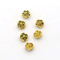Five gold-tone 6mm rose spacer beads on a white background, seen from above