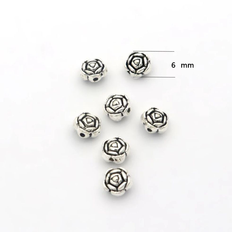Five silver-tone 6mm rose spacer beads on a white background