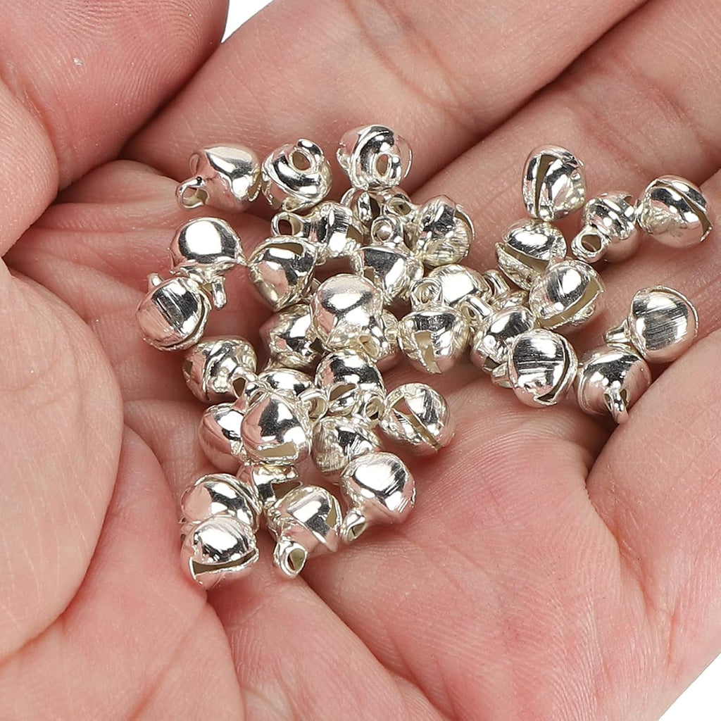 Handful of silver 6mm metal jingle bells held in an open palm