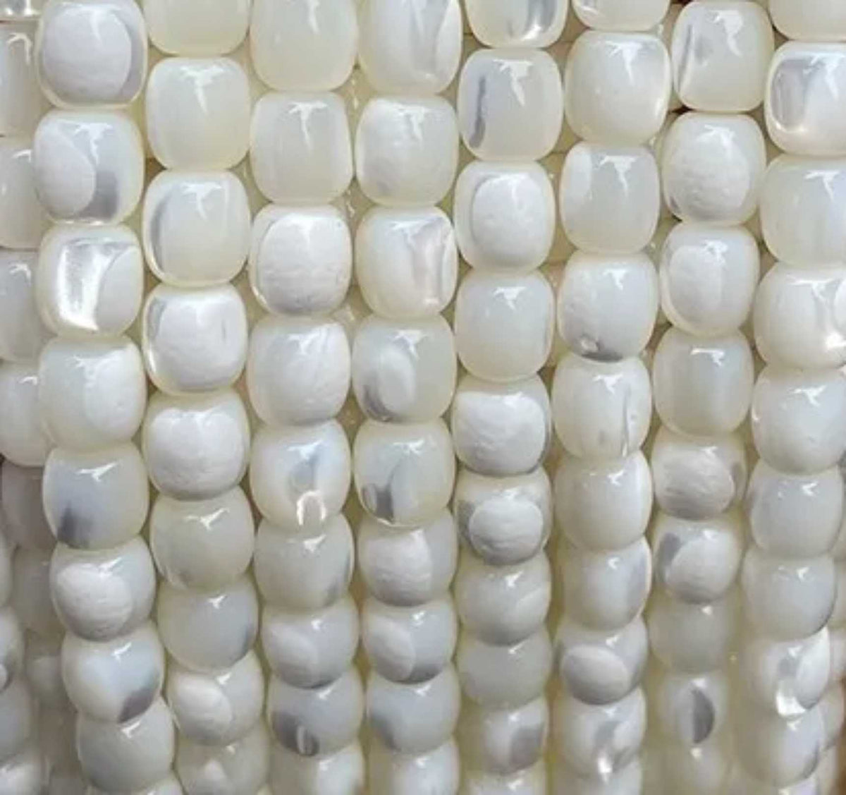 Rows of white 6mm mother of pearl cube bead strands, laid side by side