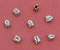Silver-tone 6 x 7mm leaf spacer beads on a red background, seen from above