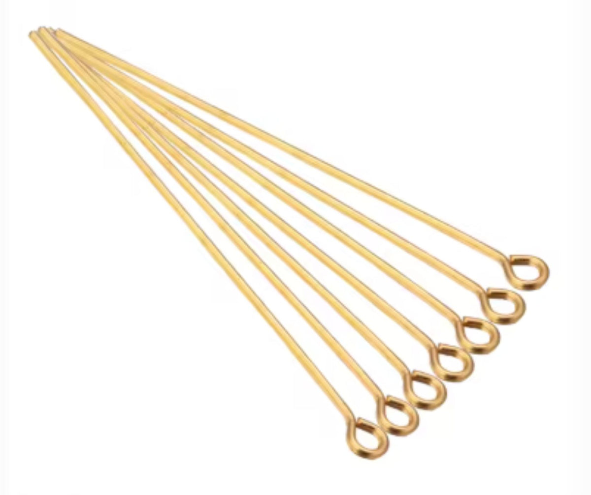 Fan of 70mm gold 20 gauge eye pins, each with a small round loop at one end, on white