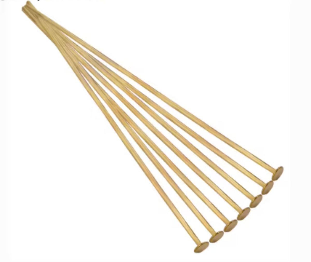 Fan of 70mm gold 20 gauge flat head pins, each with a flat disc head at one end, on white