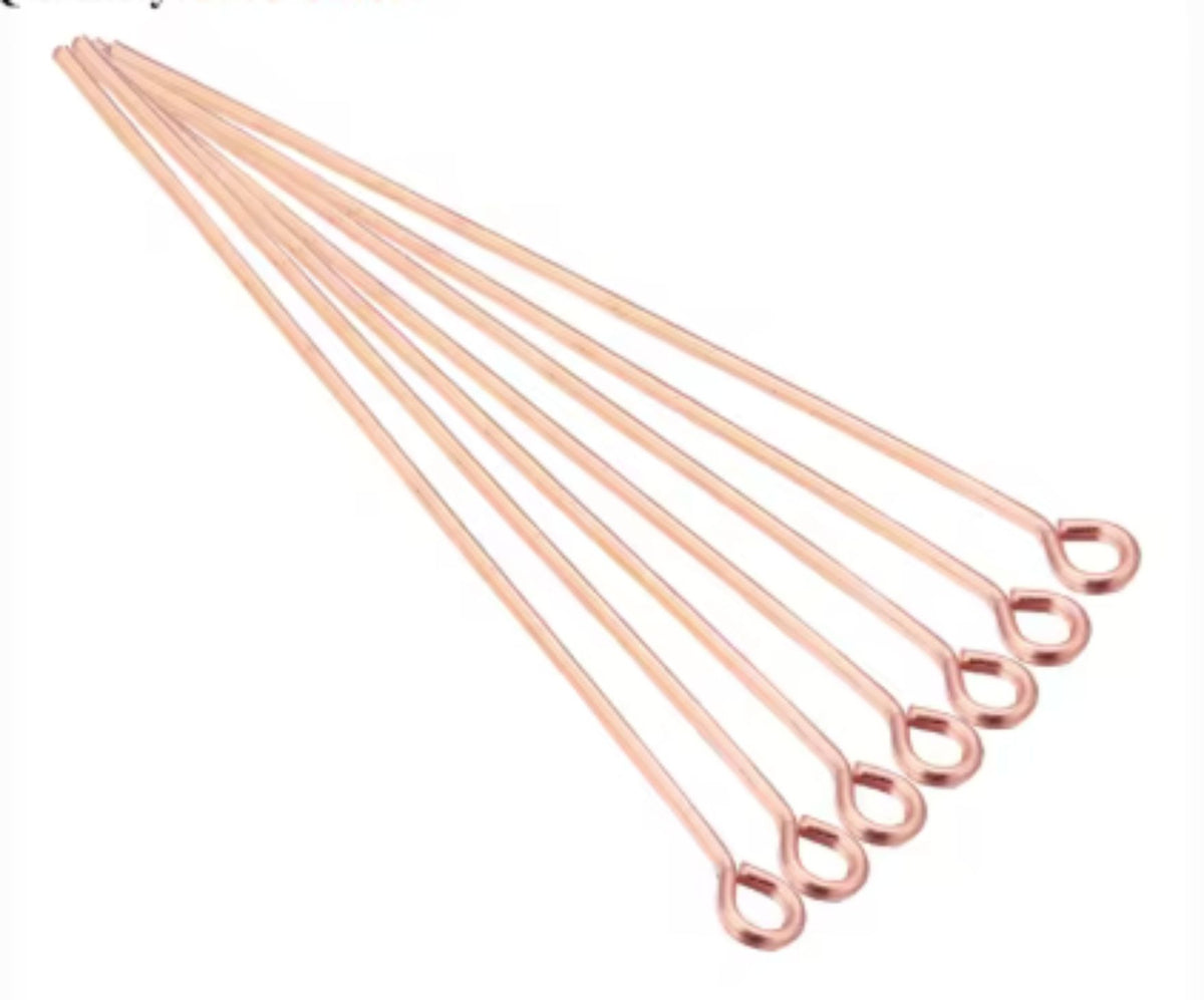 Fan of 70mm rose gold 20 gauge eye pins, each with a small round loop at one end, on white