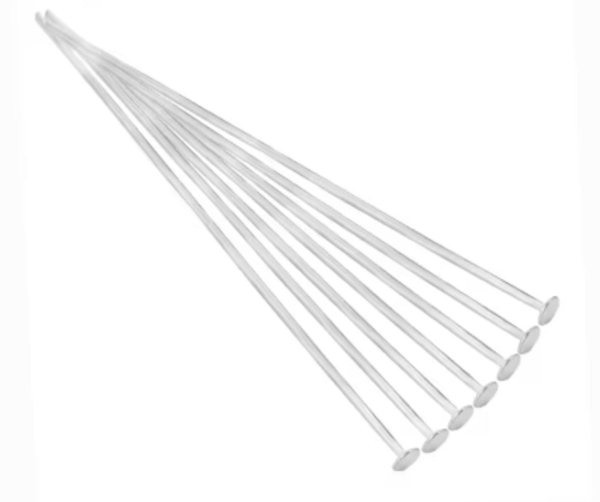 Fan of 70mm silver 20 gauge flat head pins, each with a flat disc head at one end, on white