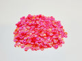 Pile of 6mm round flamingo sequins with centre holes, on a white background