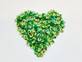 Heart-shaped pile of 6mm iridescent flower sequins in green on a white background