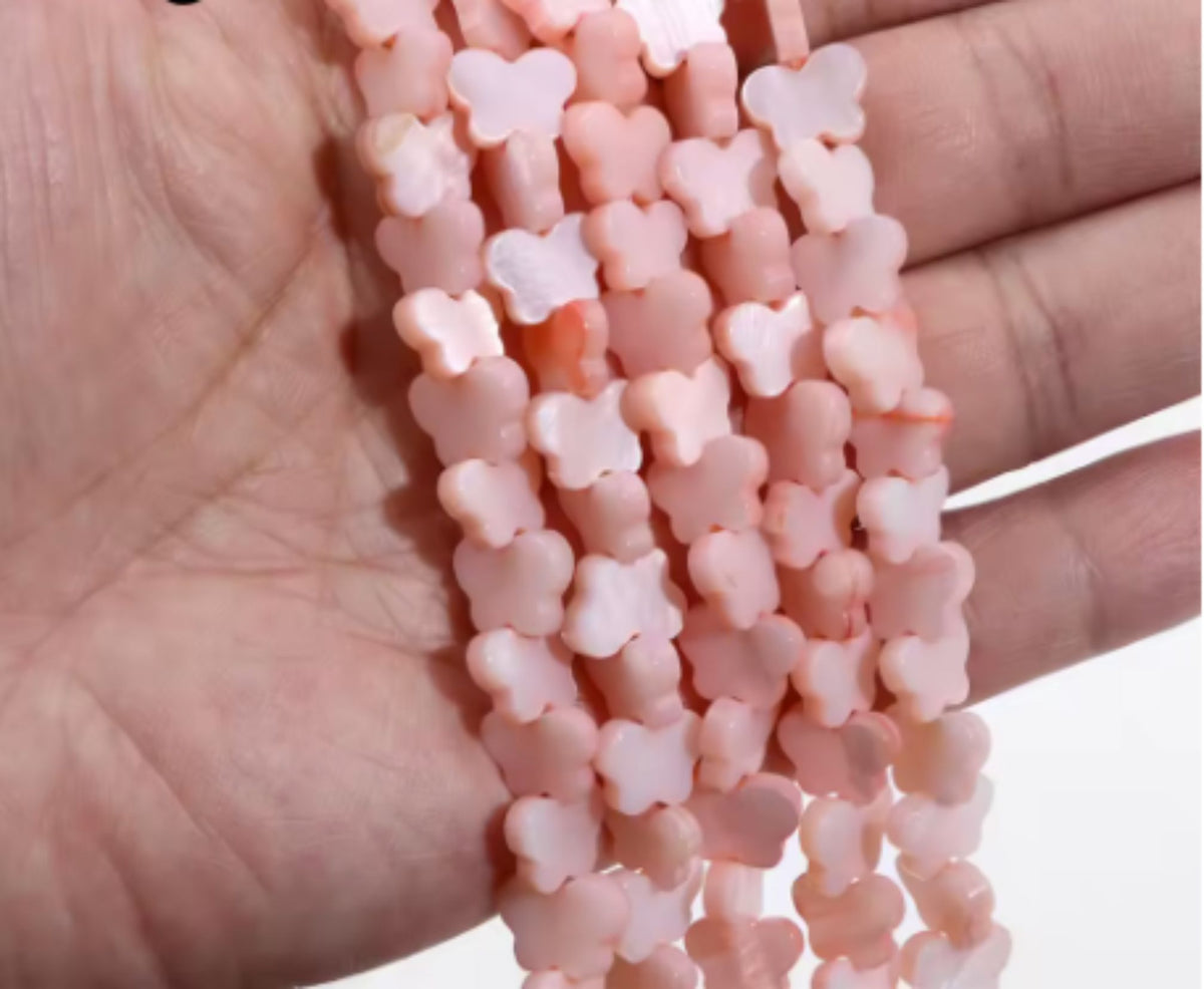 Strand of pink mother of pearl butterfly beads, 8 x 11mm, held in a hand