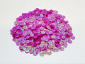 Pile of 6mm round fuchsia sequins with centre holes, on a white background