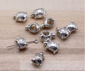 Silver-tone 9 x 14mm big-hole turtle spacer beads on wood, scattered loosely