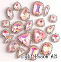 Sew-on crystal rhinestones in light peach AB, in 10 shapes with silver claw settings