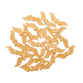 Pile of KC gold 7 x 24mm angel wing spacer beads on a white background