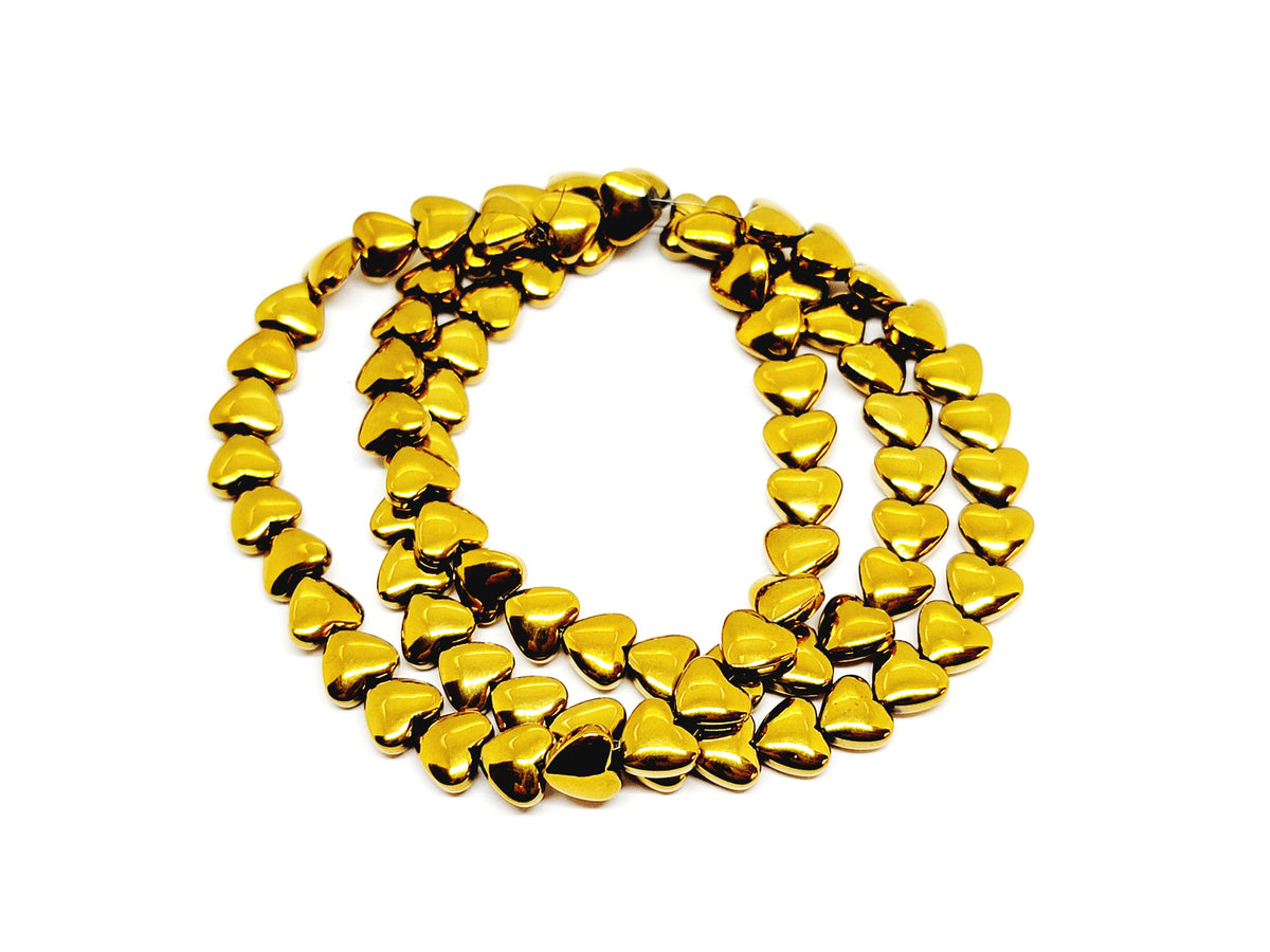 Strand of 6mm antique gold hematite heart beads coiled on a white background