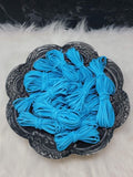 Bundles of 2.7mm aqua suede leather lacing coiled on a dark scalloped dish