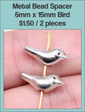 Two silver-tone 5 x 15mm bird spacer beads held between fingers