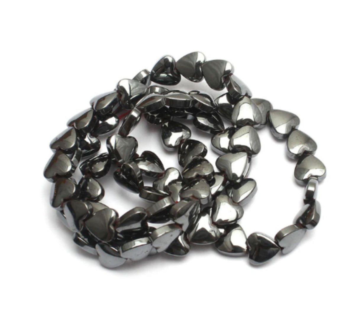 Strand of 6mm black hematite heart beads coiled on a white background