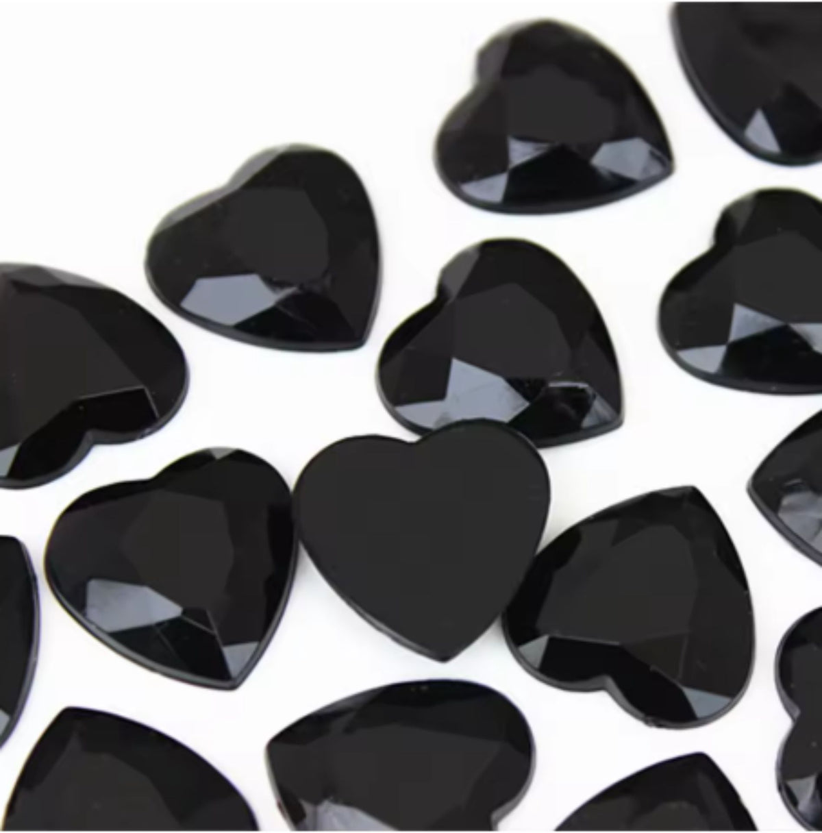 Pile of 20mm faceted black resin heart gem cabochons (cabs), one flipped to show the flat back