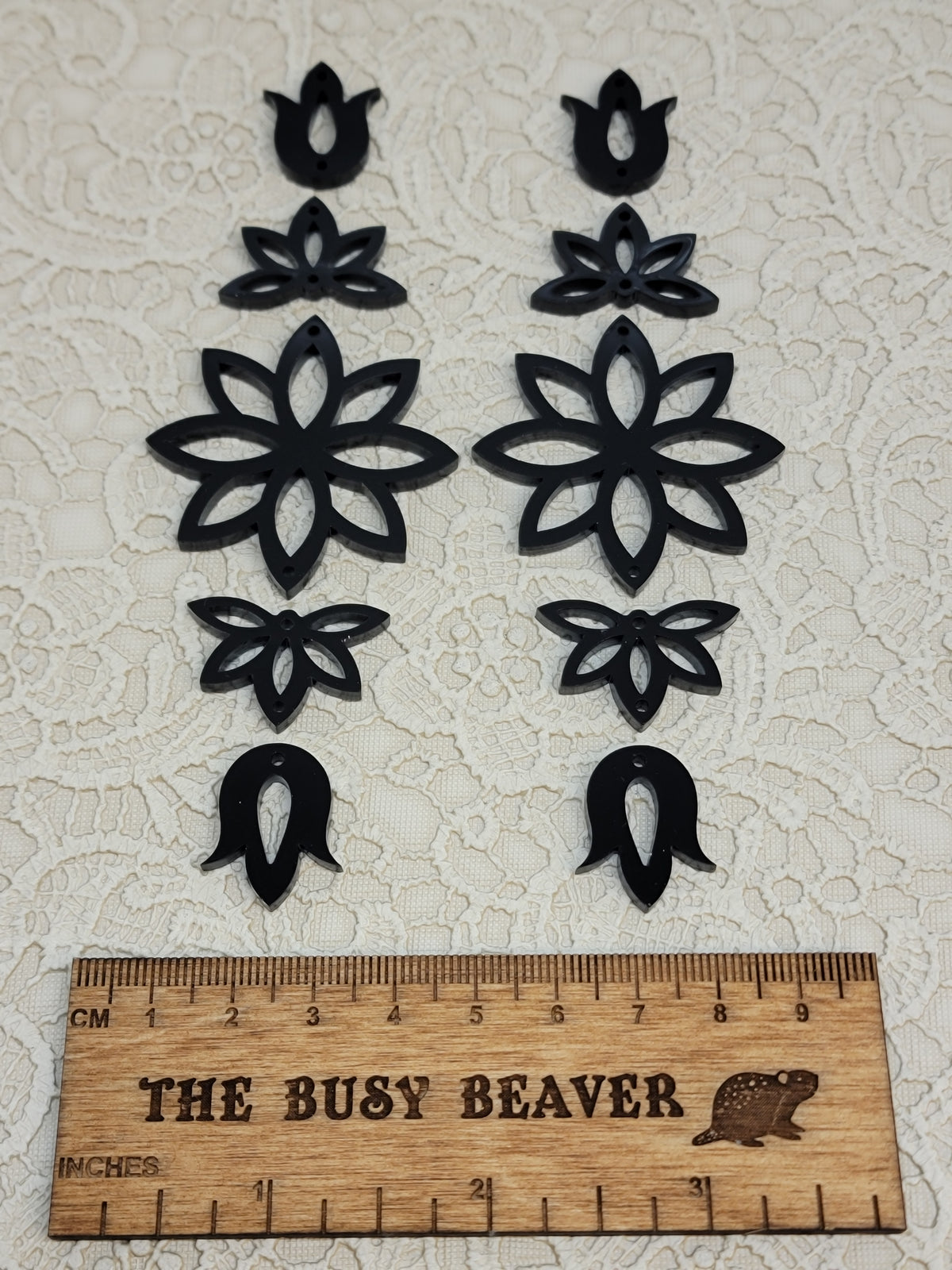 Two 5-tier acrylic flower earring sets in black, laid out top to bottom beside a ruler