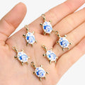Silver-tone 24mm turtle charms with blue and white flower shells held in a palm