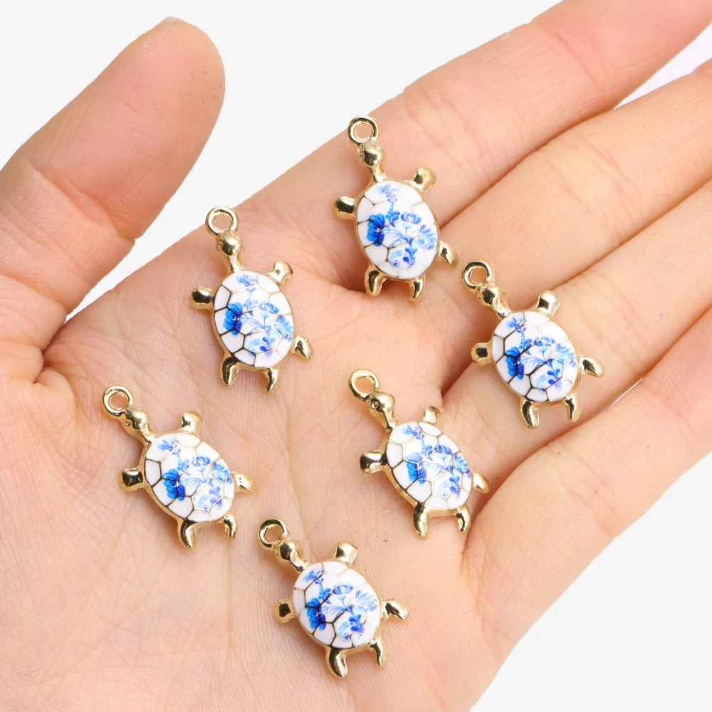 Silver-tone 24mm turtle charms with blue and white flower shells held in a palm