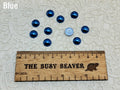 Ten 10mm blue pearl-look resin half round cabochons (cabs) beside a ruler