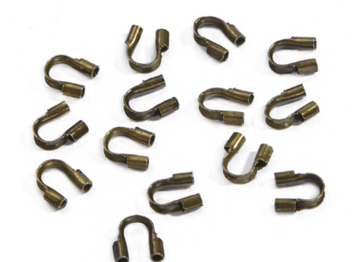 Scattered bronze horseshoe-shaped wire guards on a white background