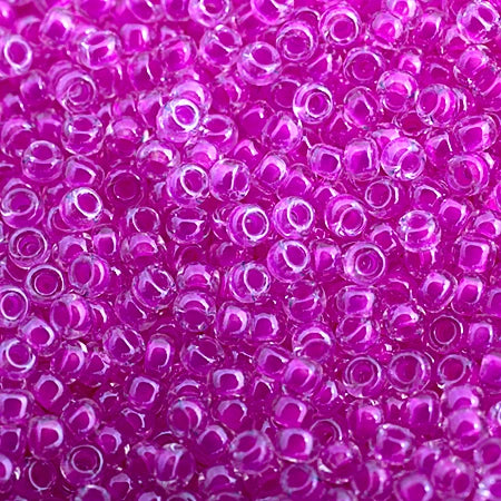 Close-up of Miyuki 11/0 glass seed beads in colour-lined fuchsia luminous neon