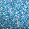 Close-up of Miyuki 11/0 glass seed beads in colour-lined light blue luminous neon