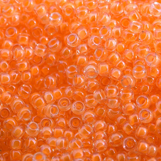 Close-up of Miyuki 11/0 glass seed beads in colour-lined orange luminous neon