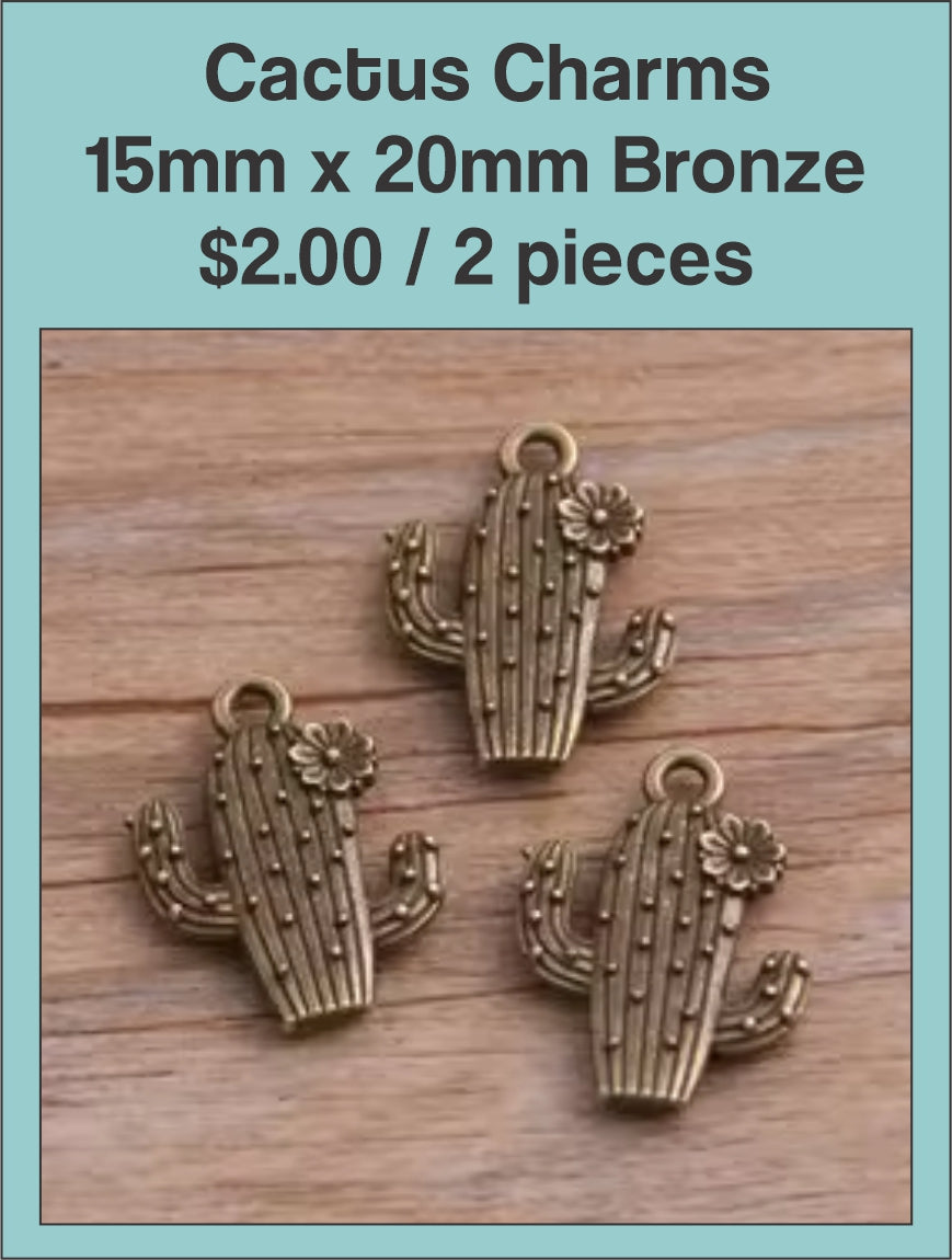 Bronze-tone cactus charms with textured detail on a wood background