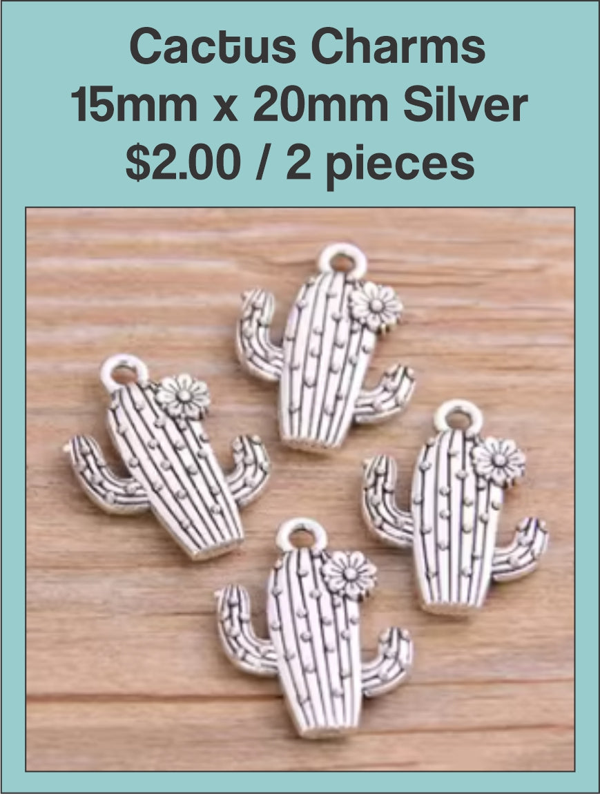 Silver-tone cactus charms with textured detail on a wood background