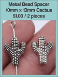 Two silver-tone 10 x 13mm cactus spacer beads threaded on a wire, held in fingers