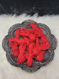 Bundles of 2.7mm cherry suede leather lacing coiled on a dark scalloped dish