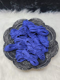 Bundles of 2.7mm cobalt blue suede leather lacing coiled on a dark scalloped dish