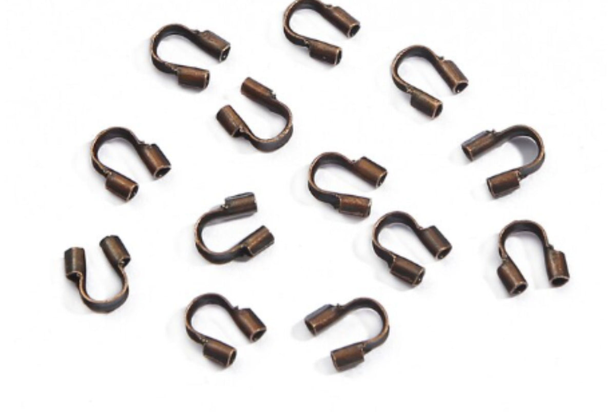 Scattered copper horseshoe-shaped wire guards on a white background