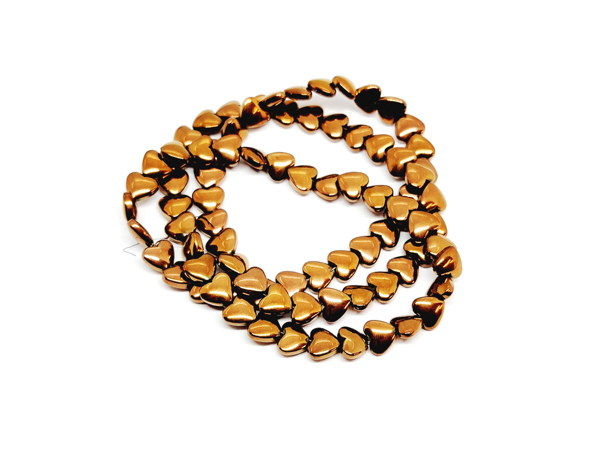 Strand of 6mm copper hematite heart beads coiled on a white background