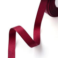 Roll of 2-inch single-faced satin ribbon in dark red with a glossy sheen