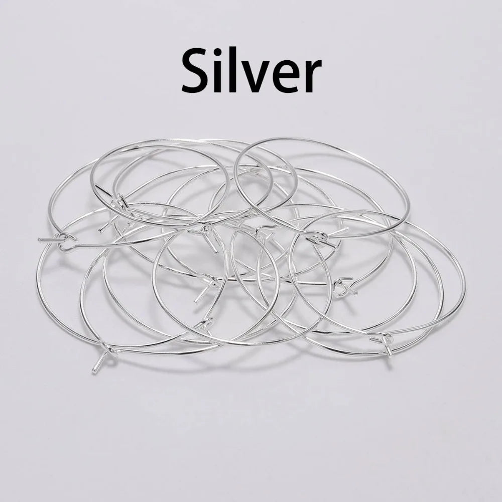 Pile of silver round wire earring hoops under a Silver label