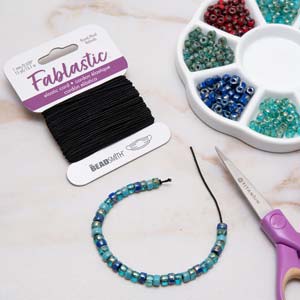 Fablastic black stretch cord with a beaded bracelet, scissors and a bead tray