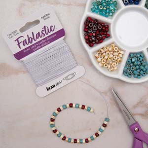 Fablastic white stretch cord with a beaded bracelet, scissors and a bead tray