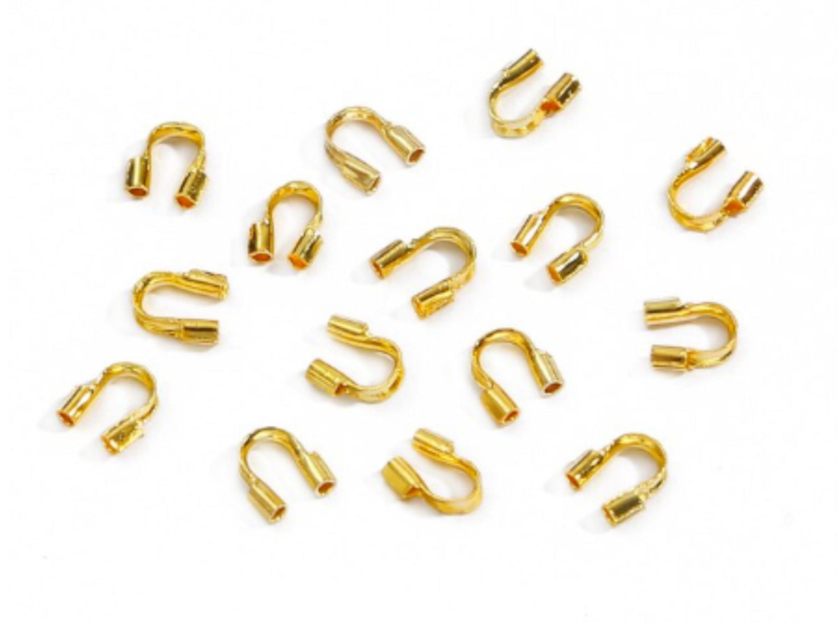 Scattered gold horseshoe-shaped wire guards on a white background
