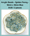 Dish of 18mm blue acrylic peony flower beads with gold-tone edging