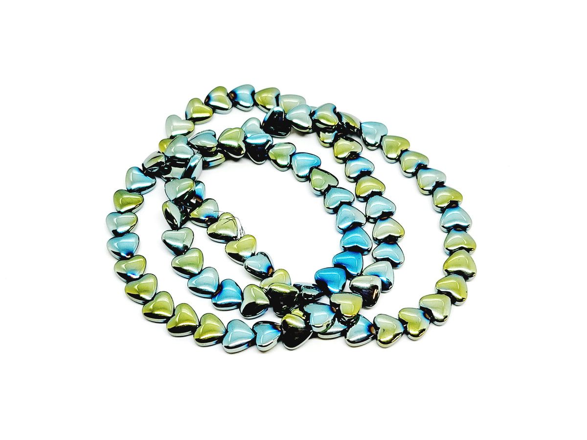 Strand of 6mm green rainbow hematite heart beads coiled on a white background