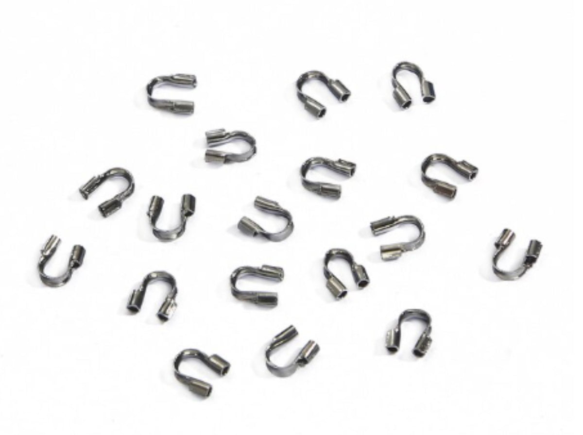 Scattered gunmetal horseshoe-shaped wire guards on a white background