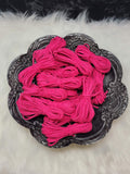 Bundles of 2.7mm hot pink suede leather lacing coiled on a dark scalloped dish
